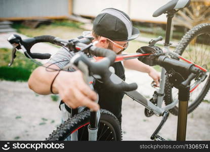 Bicycle mechanic repair bike, top view. Cycle workshop outdoor. Bicycling sport, bearded service man work with wheel