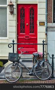 Bicycle near door of old house in Amsterdam street. Bicycles are the very popular means of transport in Netherlands. Amsterdam, Netherlands. Bicycle near door of old house in Amsterdam street