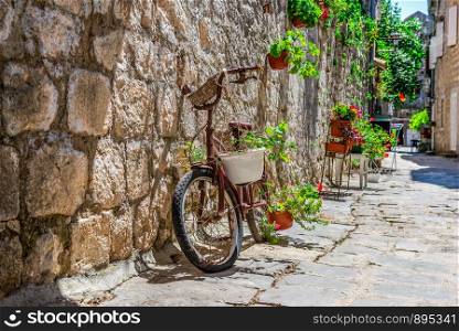 Bicycle on old street with flowers in summer Perast, Montenegro. Bicycle on street in Perast