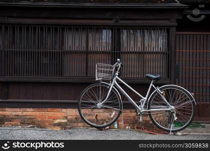 Bicycle parked in front of traditional Japanese wooden house on historic Takayama old town street, Gifu, Japan.