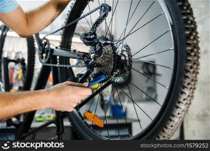 Bicycle repair in workshop, man setting up cassette closeup. Mechanic in uniform fix problems with cycle, professional bike repairing service. Bicycle repair, man setting up star cassette
