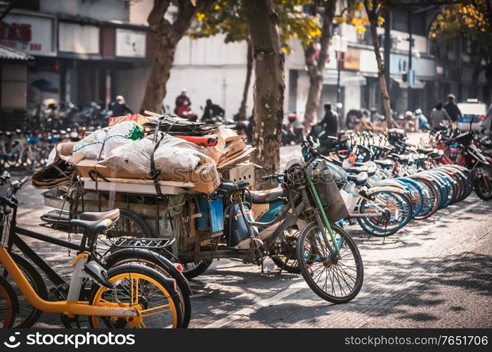 Bicycle with waste and share electric bikes parked on the sidewalk, Hangzhou, China. Bicycle with waste on the sidewalk, Hangzhou, China