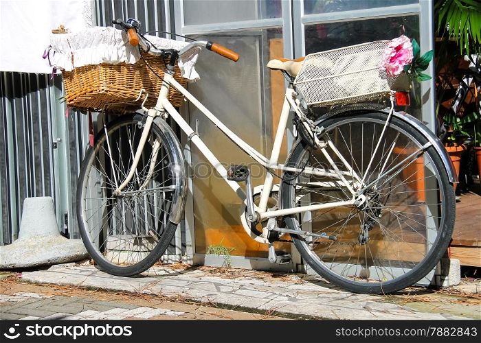 Bicycle with wicker basket stands near wall