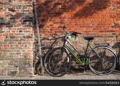 Bicycles on the pavement near brick wall in Brugges, Belgium&#xA;