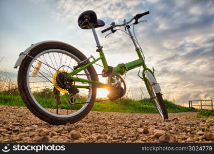 Bicycles parked on a dirt road during sunset.