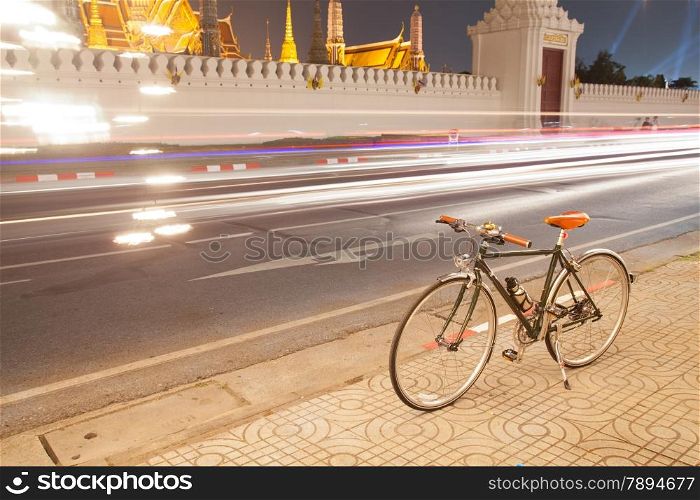 Bicycles parked on the roadside. lights of a car traveling on the road. Palace, Wat Phra Kaew