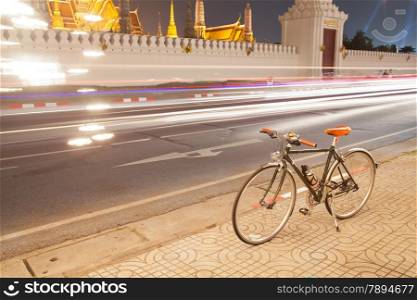 Bicycles parked on the roadside. lights of a car traveling on the road. Palace, Wat Phra Kaew