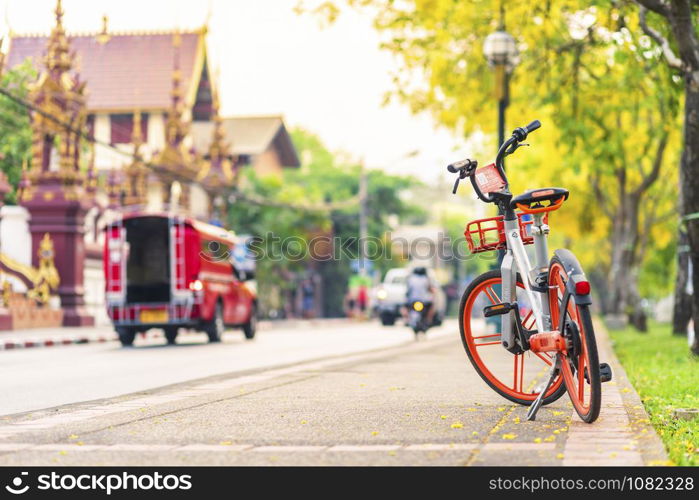 Bicycles parked travel service or Public Area in City for Tourist lot in city moat to busy street with many red taxi and temple of the evening in Chiang Mai,Thailand. By people to Ride by Scan QR Code connect to mobile application