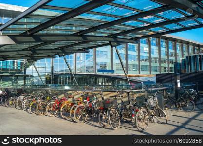 Bicycles parking by the Kastrup airport building under glass canopy in evening sunshine, Copenhagen, Denmark