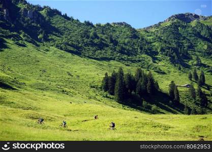 Bicyclists on the green slope of mount in Switzerland
