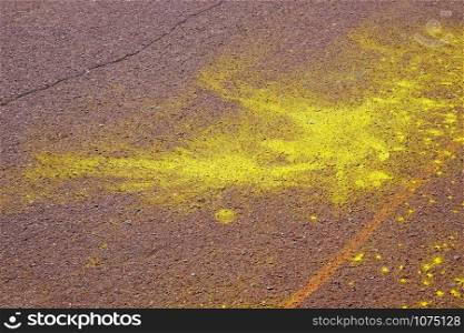 Big and small yellow shapeless spot of bright yellow on grainy brown asphalt road surface