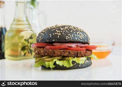 Big Black burger. Black burger with beef meat cheese lettuce onion, tomato and sauce on white table