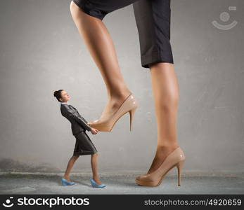 Big boss woman steping on colleague . Businesswoman foot stepping on tiny businesswoman presenting power concept