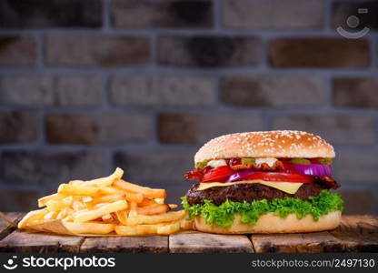 Big burger in classic american style with hot grilled patty with melted cheese on top, tomato, onion, sauces and fried chips.