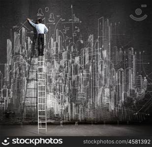 Big business plan. Rear view of businessman standing on ladder and drawing business sketch on wall