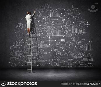 Big business plan. Rear view of businesswoman standing on ladder and drawing business sketch on wall