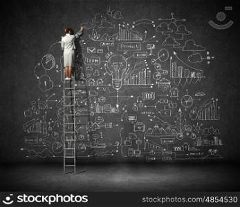 Big business plan. Rear view of businesswoman standing on ladder and drawing business sketch on wall