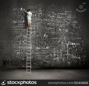 Big business plan. Rear view of businesswoman standing on ladder and drawing business sketch on wall