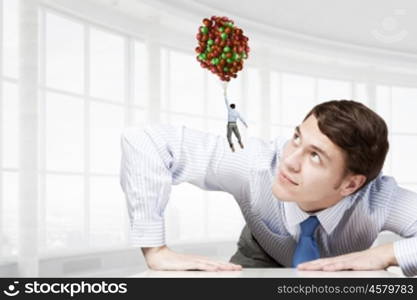 Big businessman peeping from under table. Big boss looking at people flying on air balloon