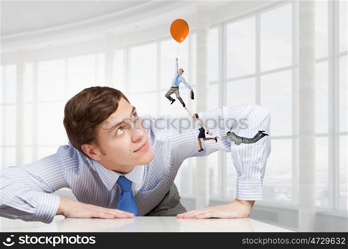 Big businessman peeping from under table. Big boss looking at people flying on air balloon