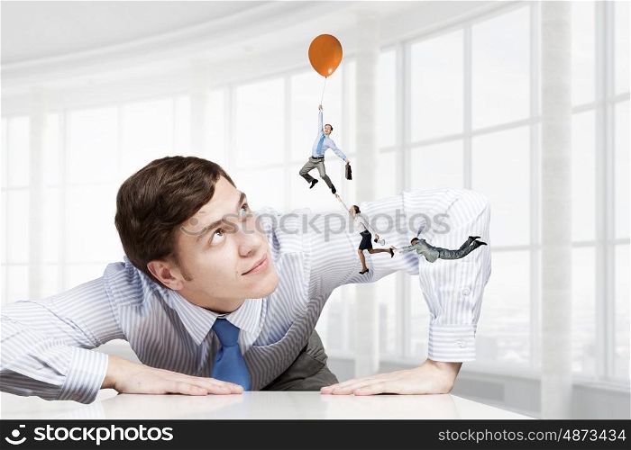 Big businessman peeping from under table. Big boss looking at people flying on air balloon