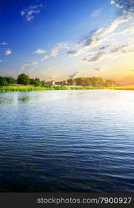 Big calm river near village at sunrise