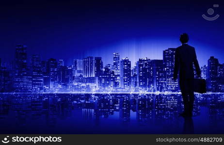 Big city life. Businessman standing with back against night city panoramic view