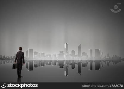 Big city never sleeps. Businessman standing with back against night city panoramic view