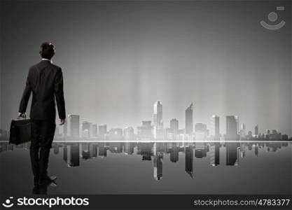 Big city never sleeps. Businessman standing with back against night city panoramic view