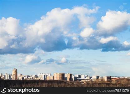 big clouds in blue spring sky over city