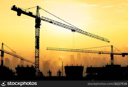 Big cranes and building construction against beautiful dusky sun. Big cranes and building construction against beautiful dusky sunset sky with cityscape in background.