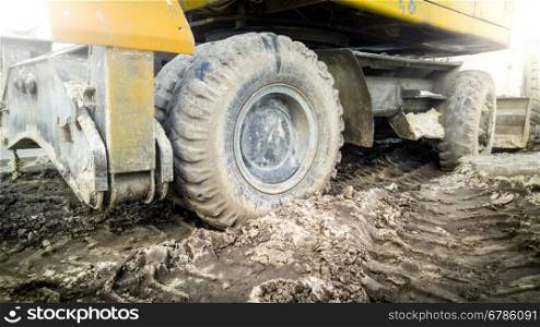 Big excavator wheels covered with mud on building site