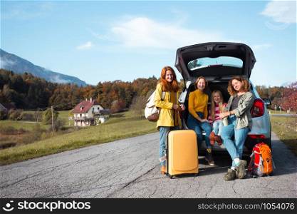 big family trip - happy girls travel by car. mamma with daughters sitting in the boot