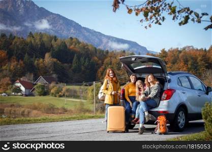 big family trip - happy girls travel by car. mamma with daughters sitting in the boot