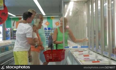 Big family with child choosing food in the section of frozen products. Shopping in the hypermarket