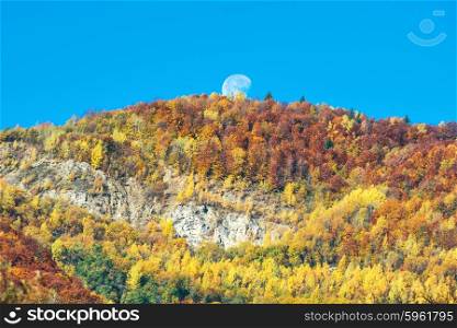 Big full moon above the mountain with autumn forest and orange trees