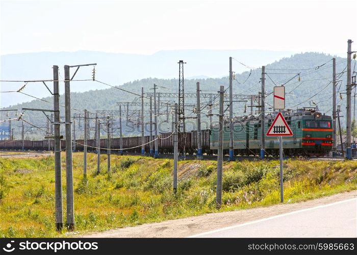 Big green electric locomotive with cars going by rail. Big green electric locomotive with cars going by rail.