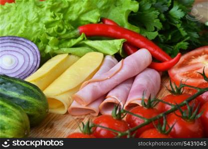 big group of meat, cheese and vegetables on a wooden table