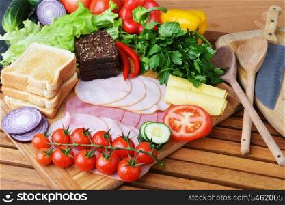 big group of meat, cheese, bread and vegetables on a wooden table