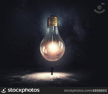 Big idea. Young businessman and big glass glowing light bulb
