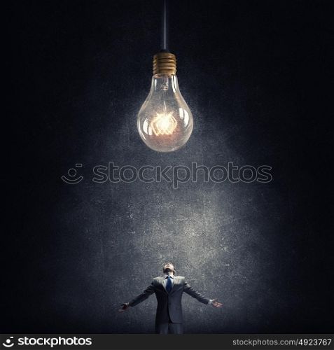 Big idea. Young businessman and glass glowing light bulb
