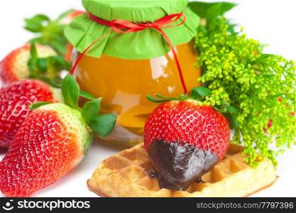 big juicy ripe strawberries in chocolate, a jar of honey and waffles isolated on white