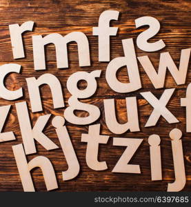 Big letters of the alphabet are chaotically scattered on wooden background. Concept of education. Scattered big letters