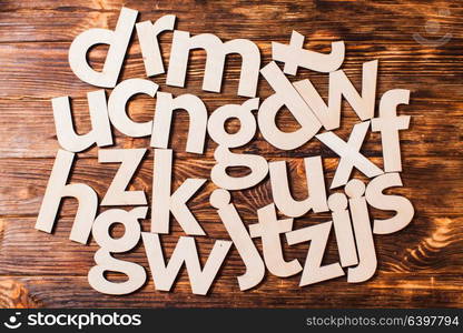 Big letters of the alphabet are chaotically scattered on wooden background. Concept of education. Scattered big letters