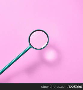 Big magnifying glass above pastel pink background with soft shadows and reflection, copy space. Search and study concept.. Magnifying glass above pink background with shadows.