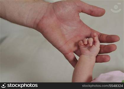 big man hand holding small baby hand
