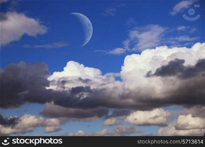 big moon in the daytime sky with clouds