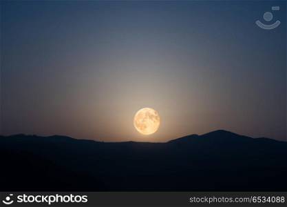 Big moon rising on night sky. Big moon rising on night sky with many stars above the mountain range