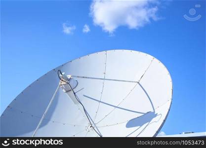 Big parabolic satellite antenna for telecommunications on a background of blue sky.. White big parabolic satellite antenna for telecommunications on a background of blue sky.