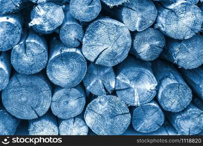 Big pile of wooden log cuts blue toned background. Color of the year 2020 classic blue toned